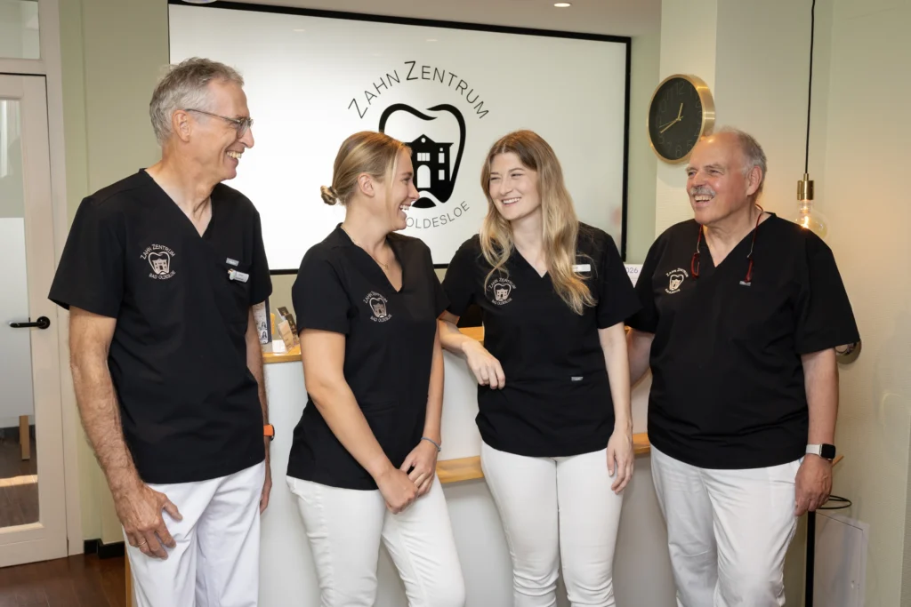 Team des Zahnarztes in Bad Oldesloe am Empfang vor der Logowand
